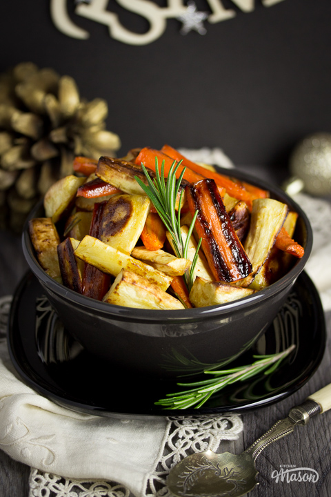 Sprigs of rosemary on a bowl of honey roast carrots and parsnips.