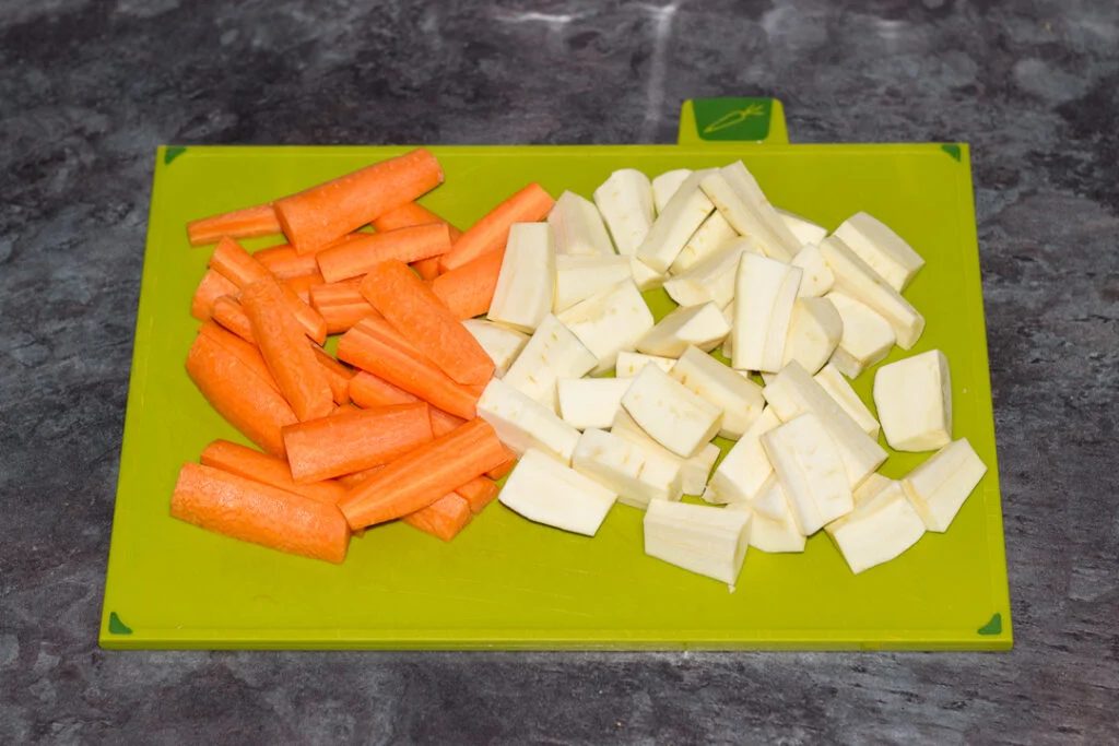 Chopped carrots and parsnips on a chopping board.