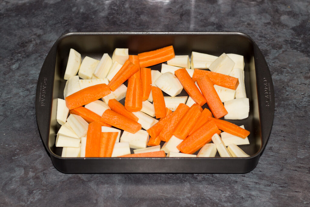 Chopped carrots and parsnips in a roasting pan.