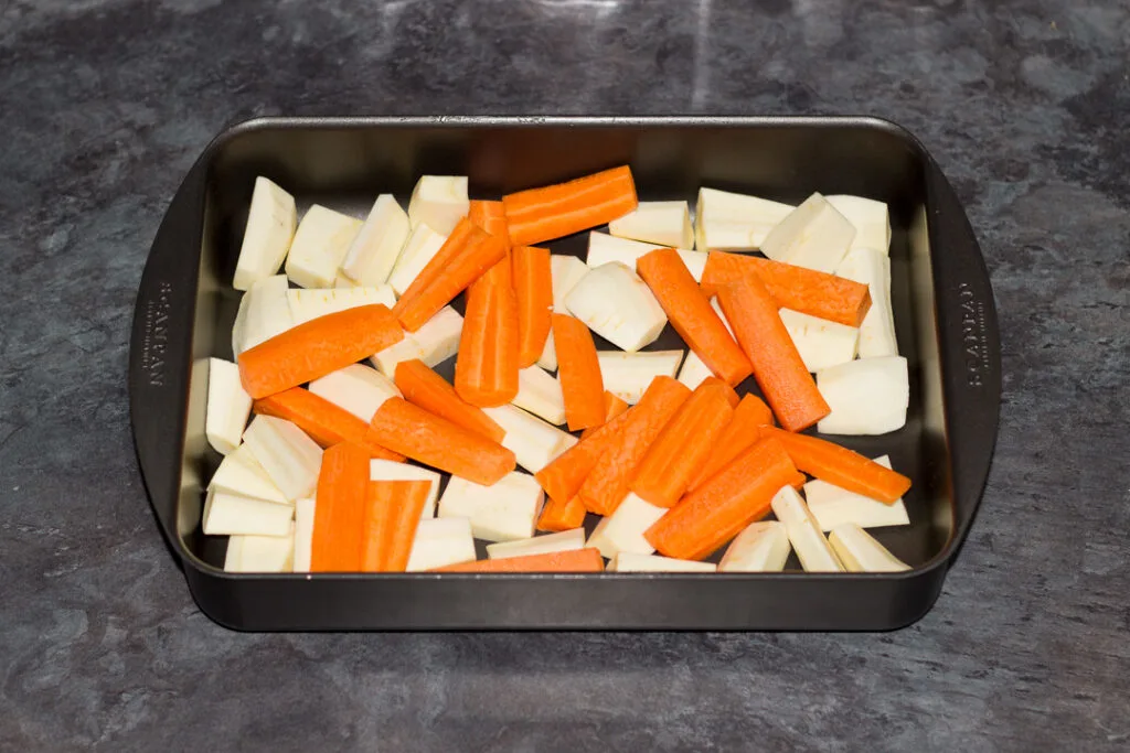 Chopped carrots and parsnips in a roasting pan.