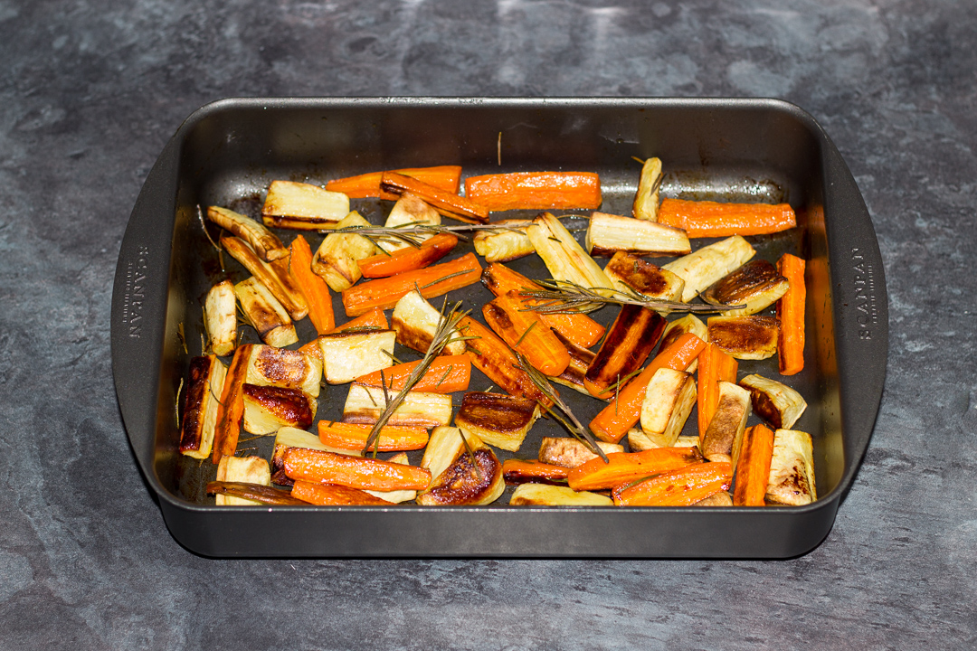 Roasted carrots and parsnips in a roasting pan.