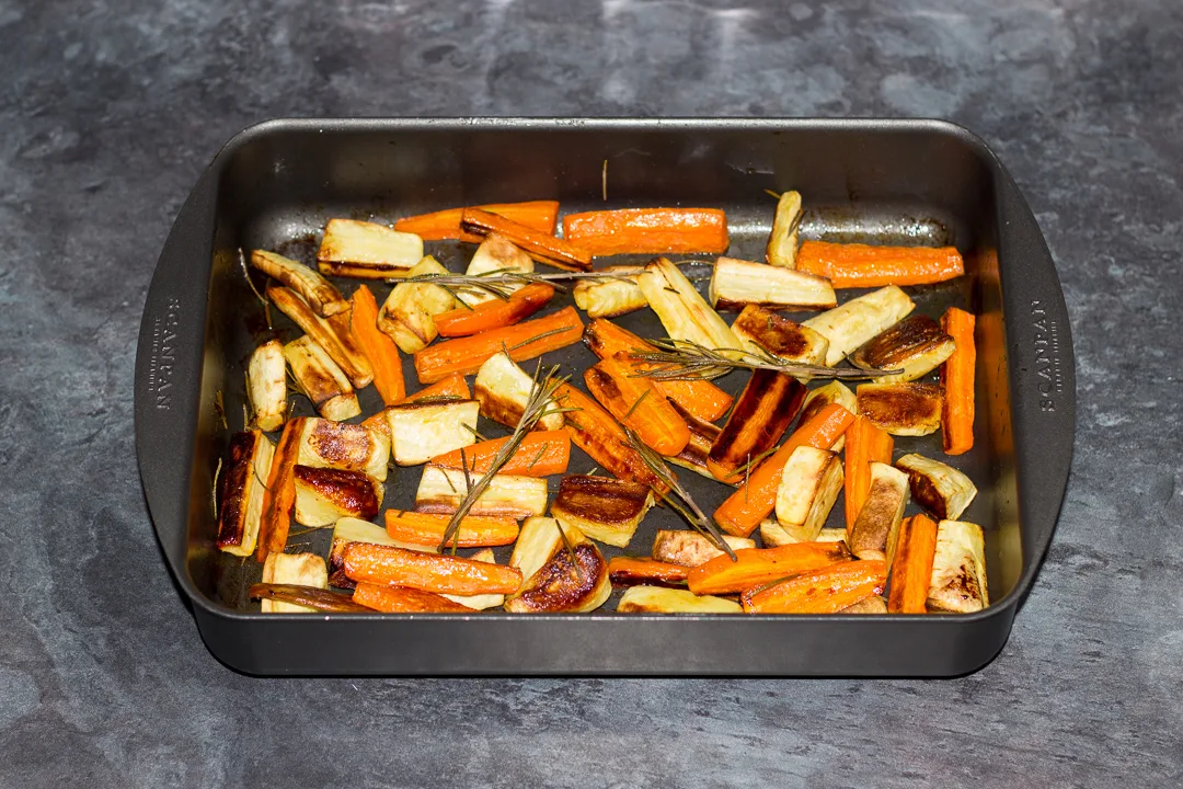 Roasted carrots and parsnips in a roasting pan.
