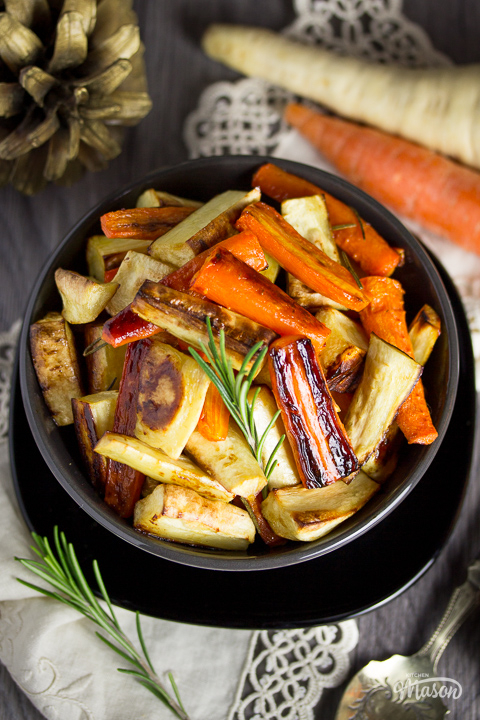 A bowl filled with honey roast carrots and parsnips, with a light brown napkin to the side.