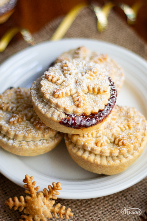 Shortcrust pastry mince pies on a white plate dusted with icing sugar.
