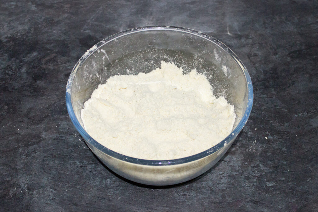 Dry ingredients for shortcrust pastry in a glass bowl.