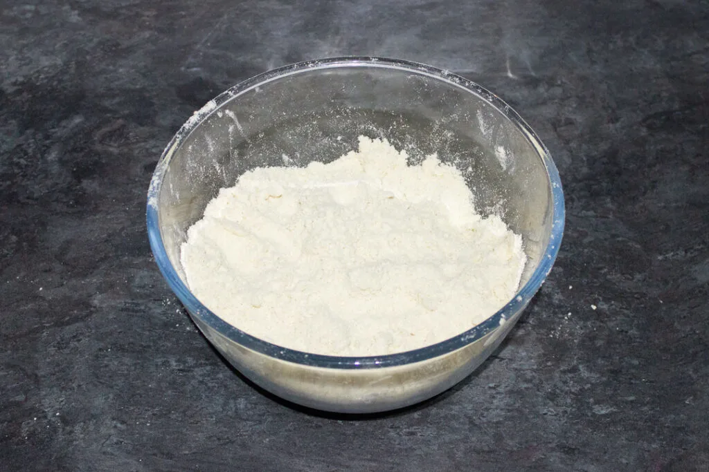 Dry ingredients for shortcrust pastry in a glass bowl.
