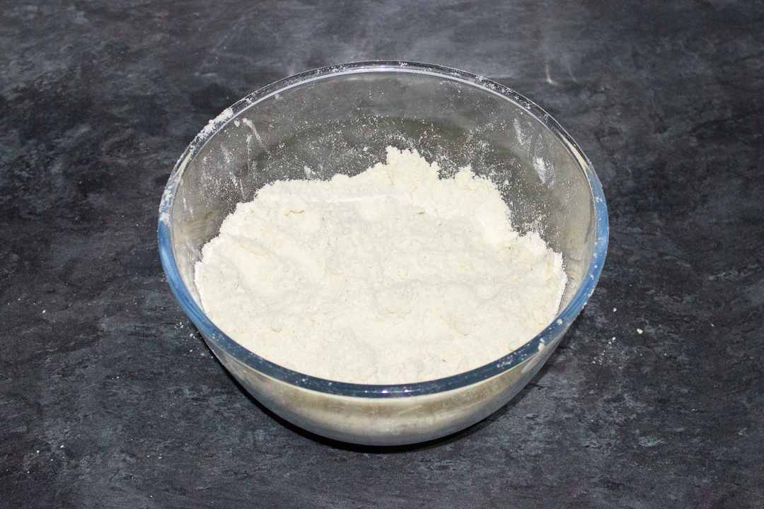 Dry ingredients for shortcrust pastry in a glass bowl.