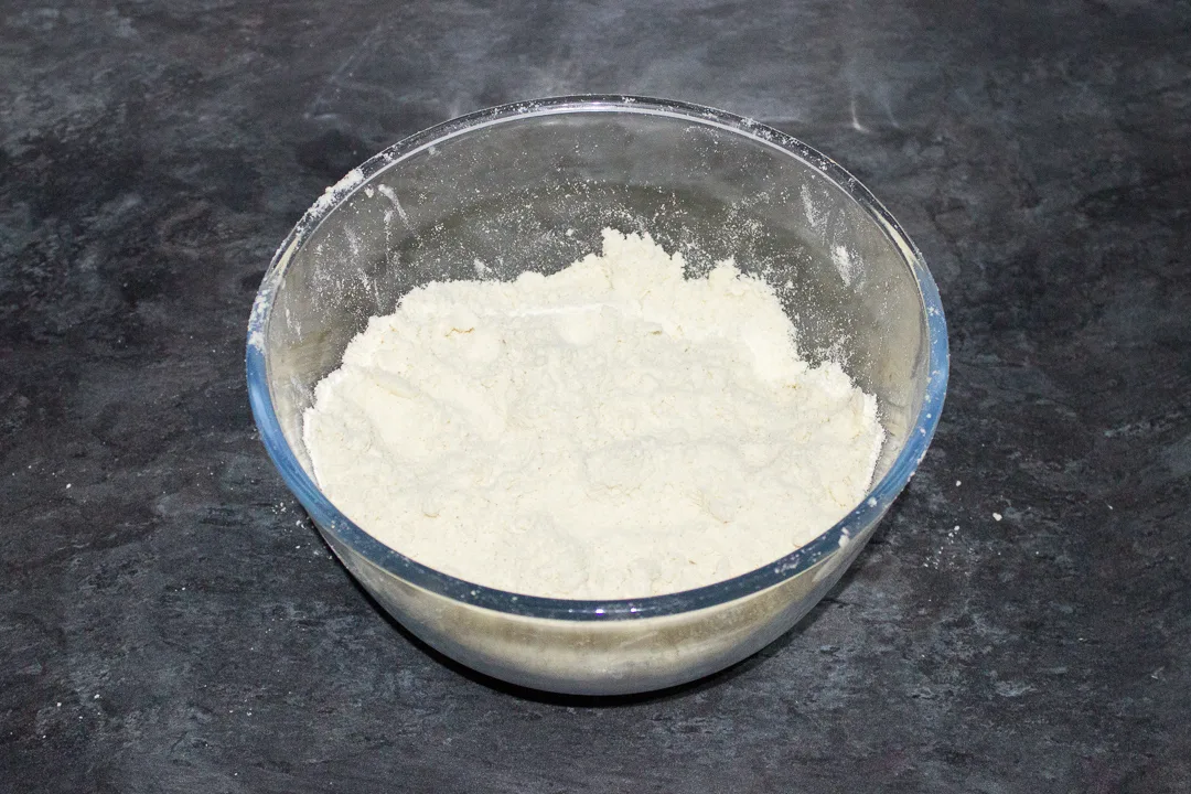 Dry ingredients for shortcrust pastry in a glass bowl.