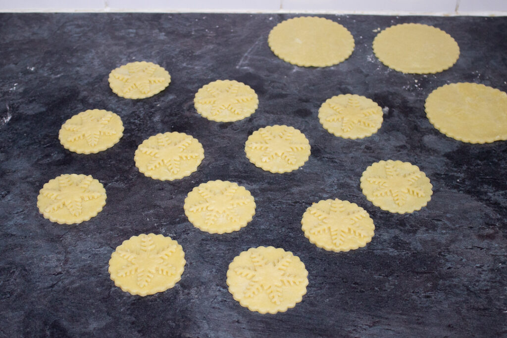 Mince pie lids with pastry snowflakes stuck to the tops.