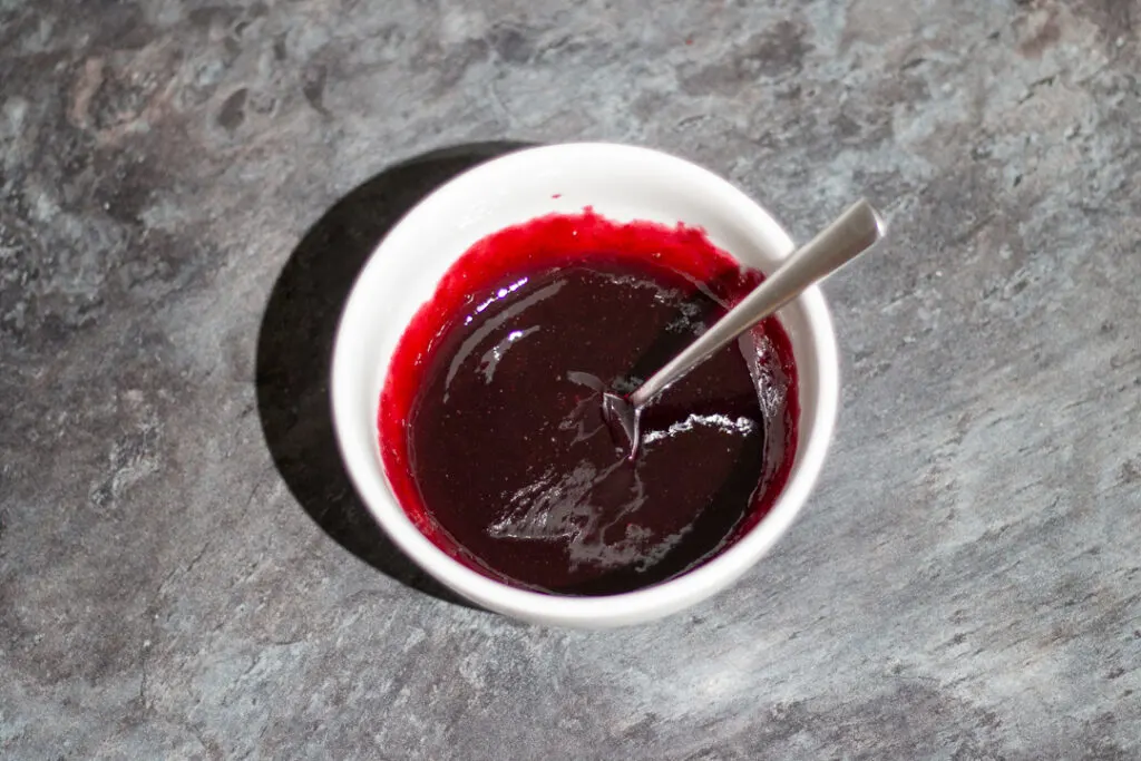 Sieved black cherry jam in a small bowl with a spoon.