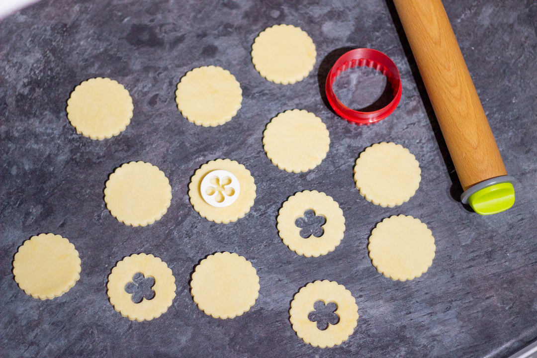 Rolled and cut biscuit rounds having the middles cut out with a flower shaped cutter.