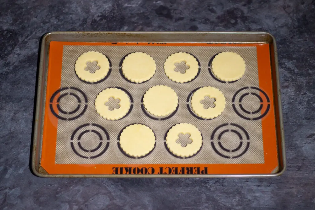 Unbaked biscuits on a lined baking tray.