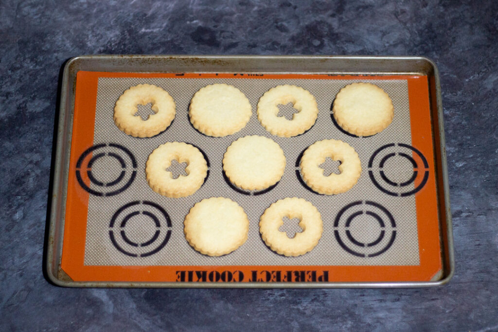 Baked biscuits on a baking tray lined with a silicone baking mat.