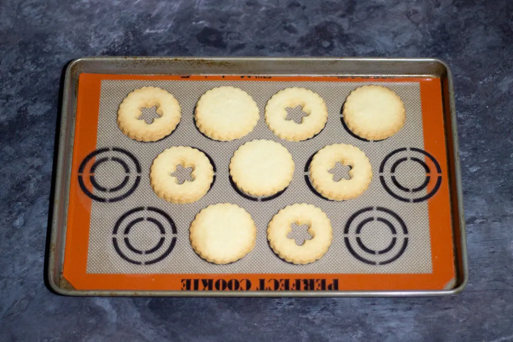 Baked biscuits on a baking tray lined with a silicone baking mat.