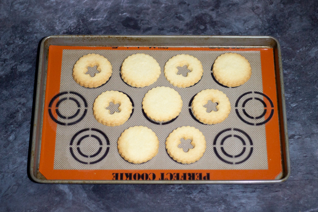 Baked biscuits on a baking tray lined with a silicone baking mat.