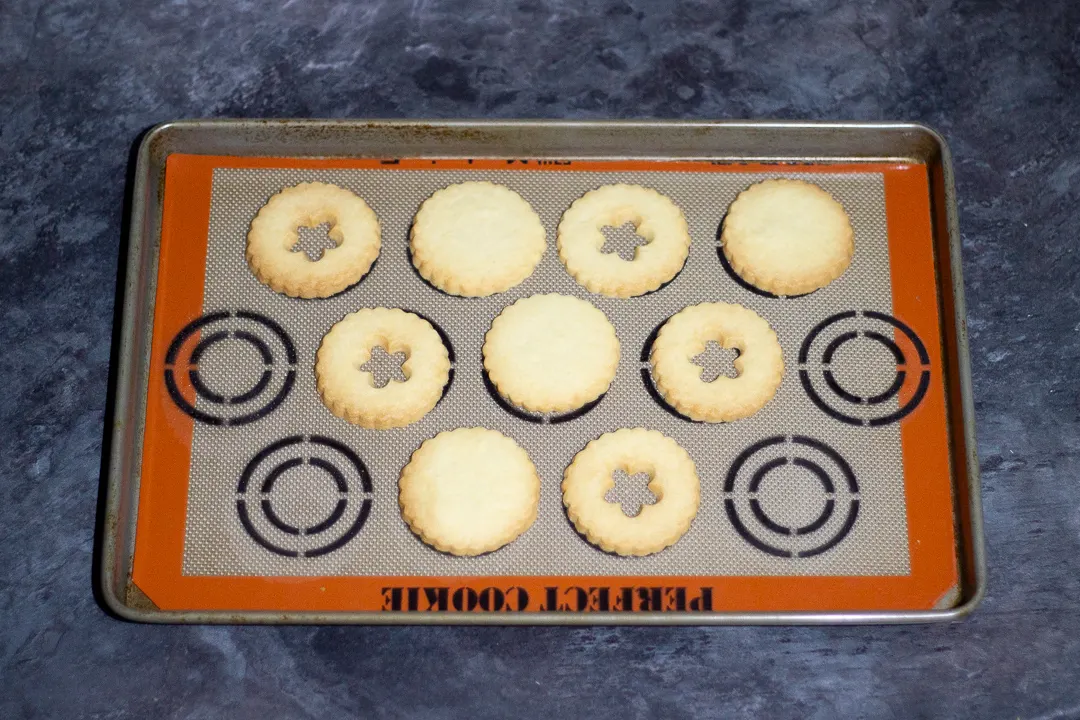 Baked biscuits on a baking tray lined with a silicone baking mat.