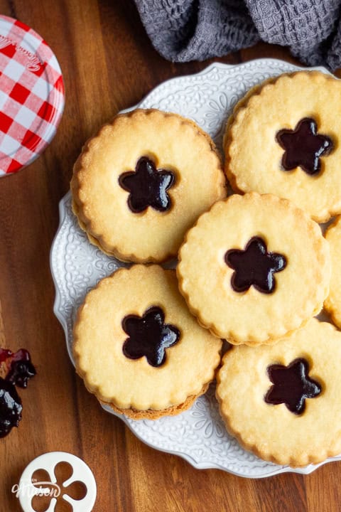 Black cherry jammy dodger biscuits on a white decorative plate.