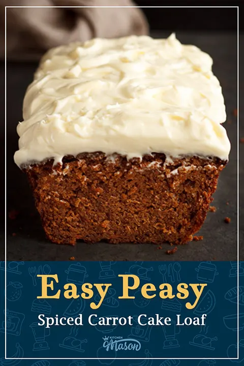 A partially sliced spiced carrot cake loaf on a work surface with a light brown linen napkin behind it.