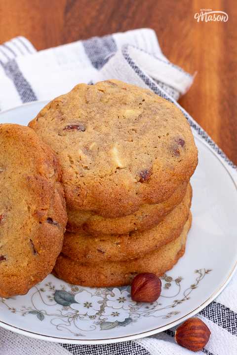 5 nut biscuits on a small flower patterned plate set over a white and grey striped tea towel.