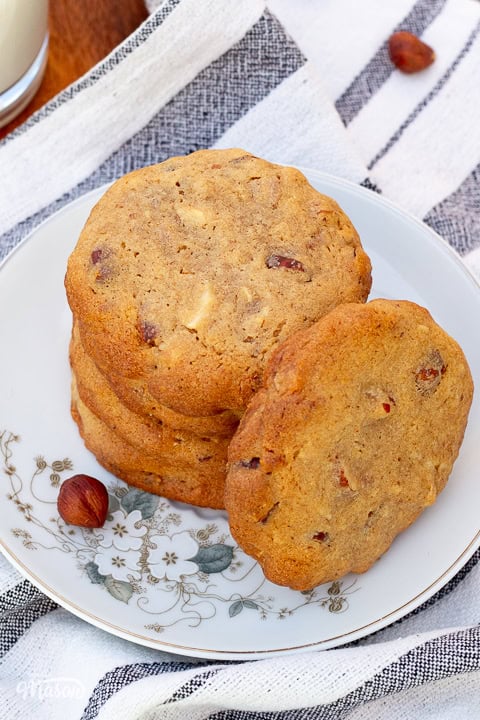 A small stack of nut biscuits on a little flower patterned plate, set on a tea towel.