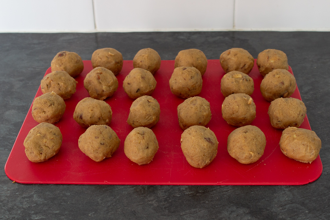 Nut biscuit dough balls on a chopping board.