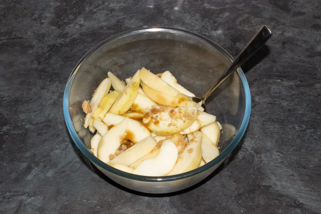 A bowl of sliced pears topped with brown sugar and lemon juice.