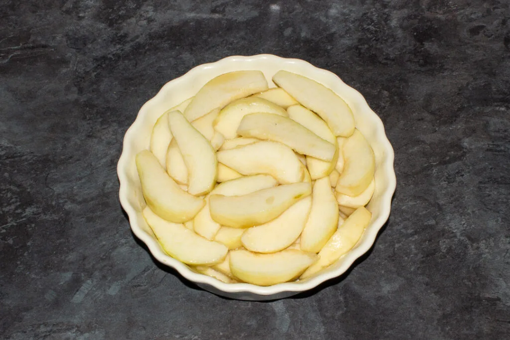 Sliced pears in a baking dish on a kitchen worktop.