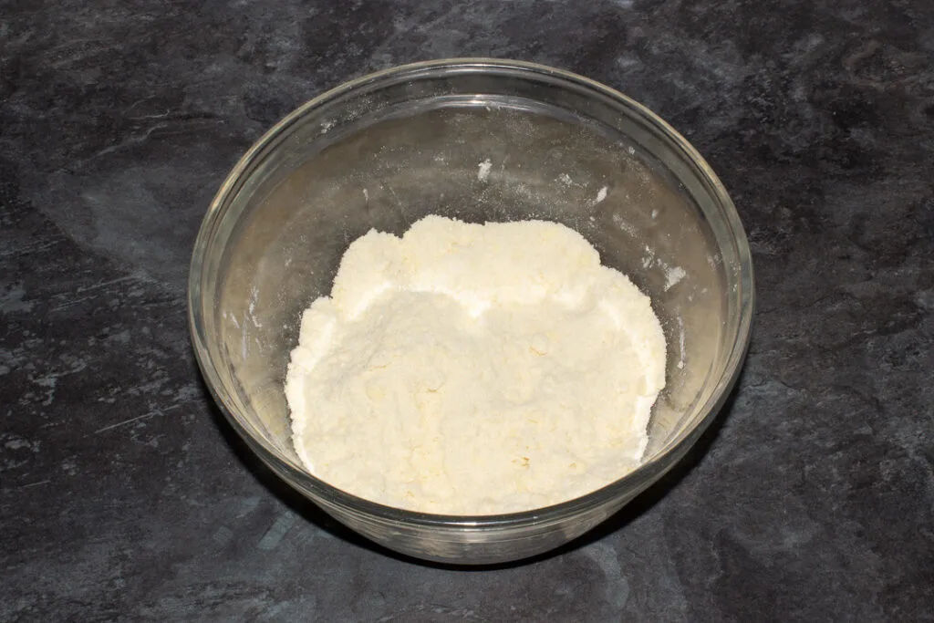 A crumble topping in a large mixing bowl on a kitchen worktop.
