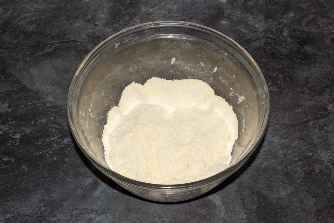 A crumble topping in a large mixing bowl on a kitchen worktop.