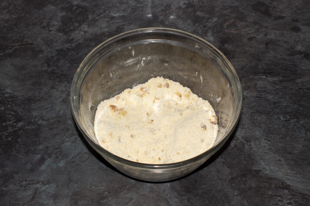 Chopped walnuts mixed into a crumble topping in a mixing bowl.