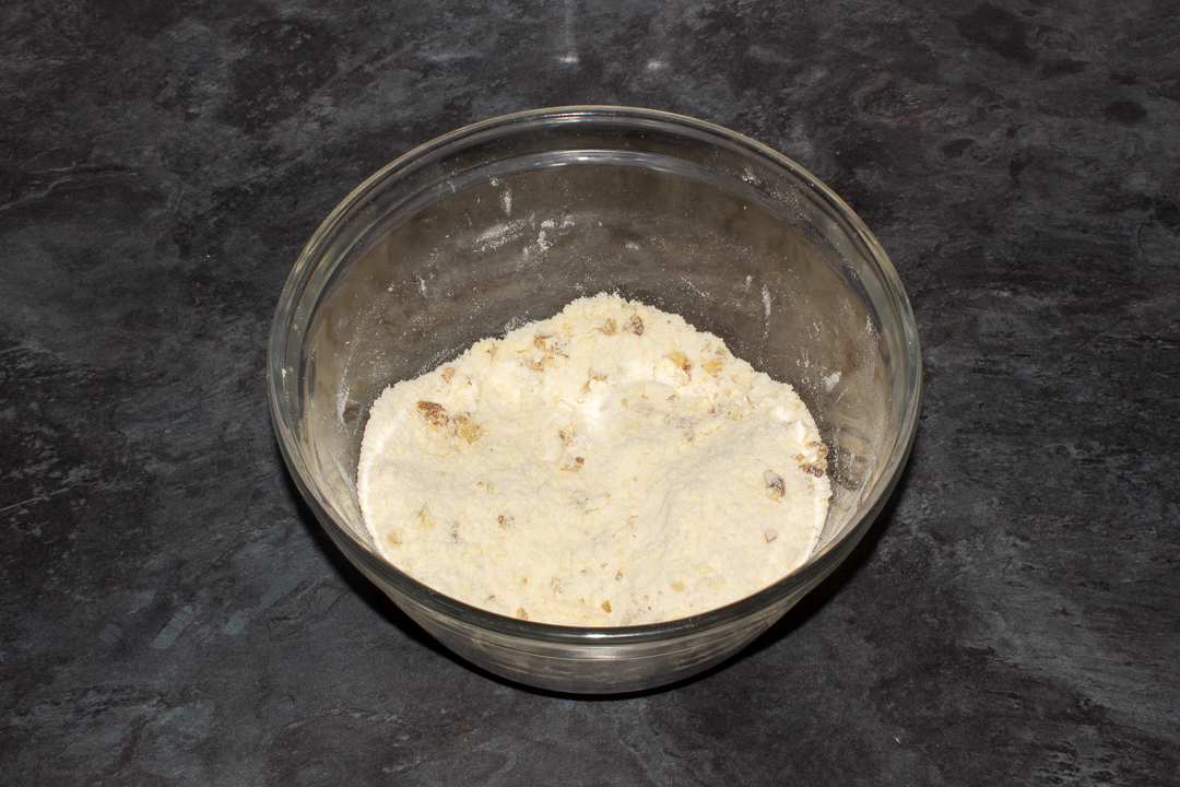 Chopped walnuts mixed into a crumble topping in a mixing bowl.