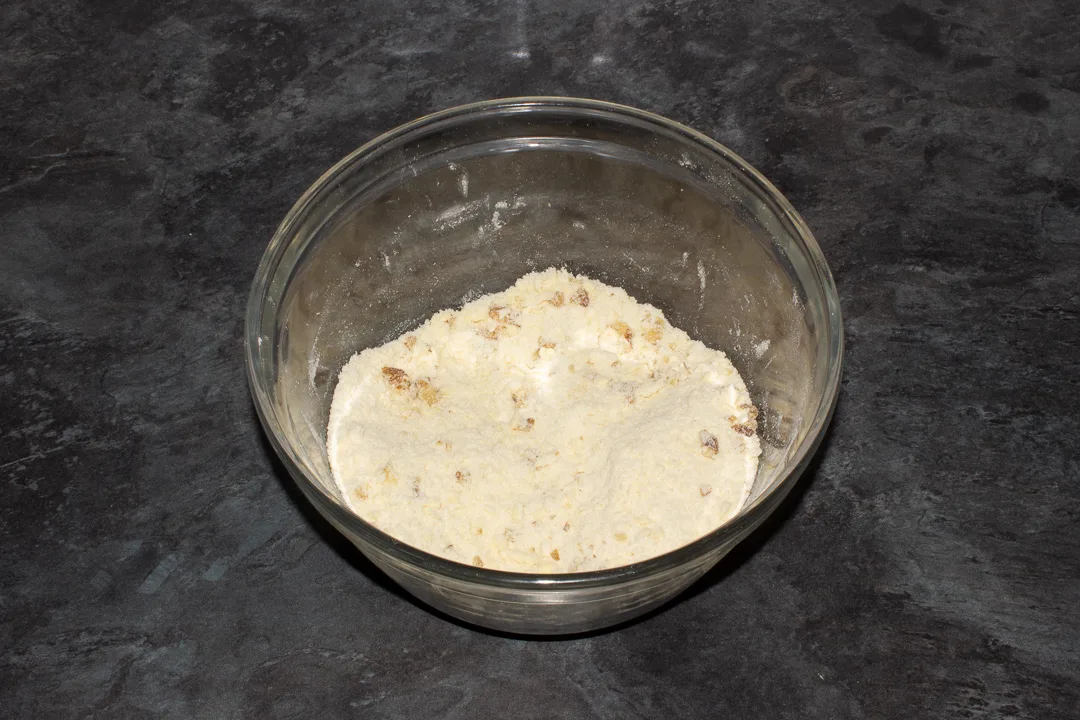 Chopped walnuts mixed into a crumble topping in a mixing bowl.