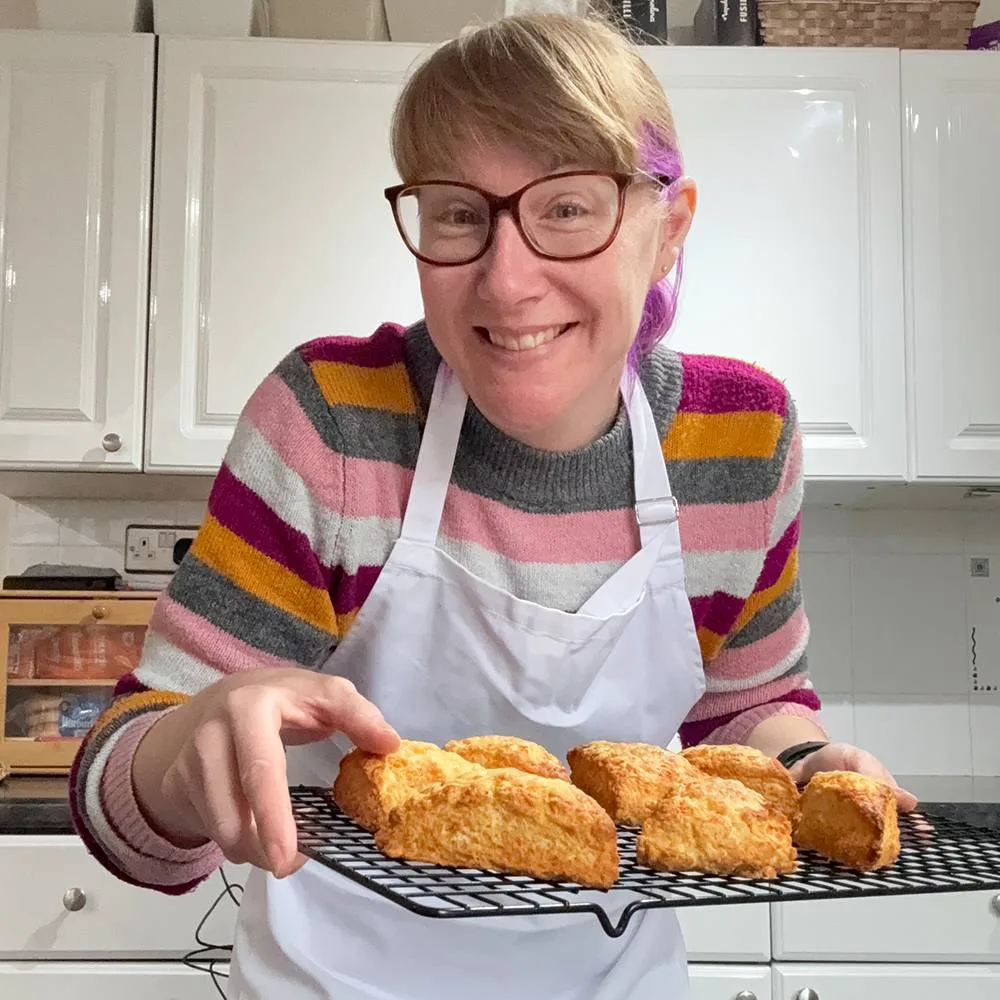 Emma holding a rack of freshly baked cheese scones that were made on a live online cook-along.