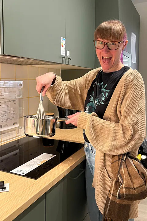 Emma having fun in an IKEA showroom kitchen, pretending to cook using their pots and pans.
