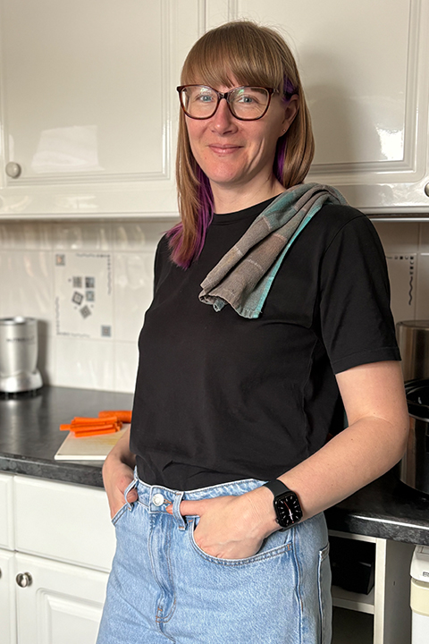 A smiling Emma in her home kitchen with a tea towel over her shoulder.