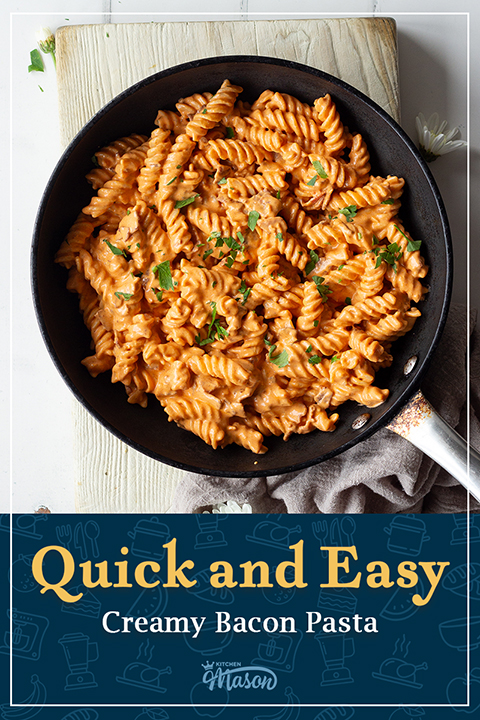 A large frying pan filled with creamy bacon pasta over a wooden board. A text overly says "Quick and easy creamy bacon pasta recipe".