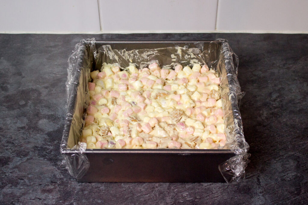 Mini Egg rocky road mixture pressed into a lined square baking tin.