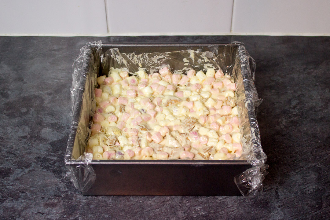 Mini Egg rocky road mixture pressed into a lined square baking tin.