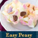 Two white chocolate Mini Egg rocky road bars on a decorative plate over a purple napkin. A text overlay says "Easy peasy Mini Egg Rocky Road".
