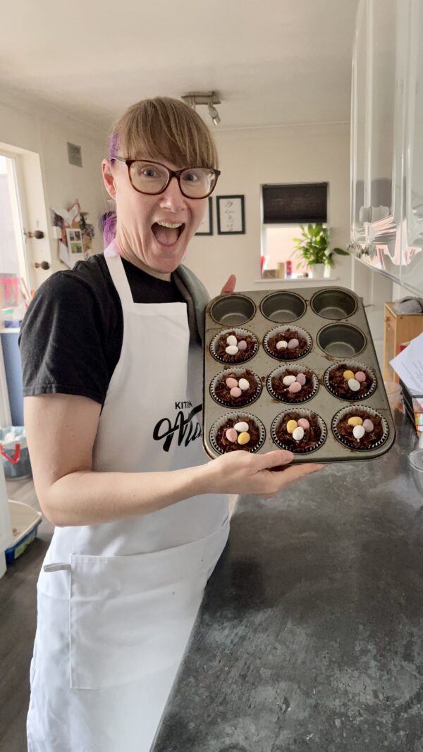 Emma in her kitchen holding a tray of freshly made Easter cornflake cakes.