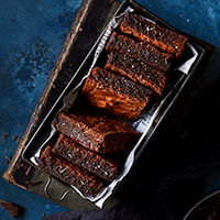 A loaf pan filled with perfectly rich and fudgy chocolate brownies set on an old book.