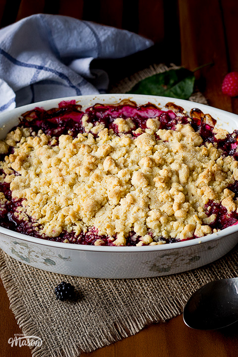 A Summer fruit crumble on hessian, with a serving spoon at the side.