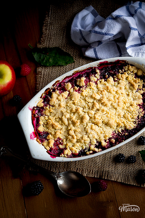 A dish filled with warm Summer fruit crumble set over hessian fabric.