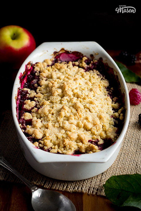 A serving spoon next to a dish filled with an inviting Summer fruit crumble.