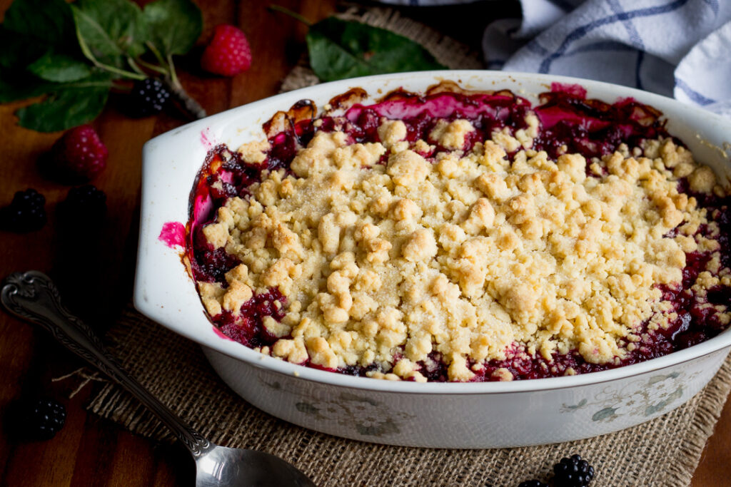 An apple berry crumble in a dish with a serving spoon to the side.