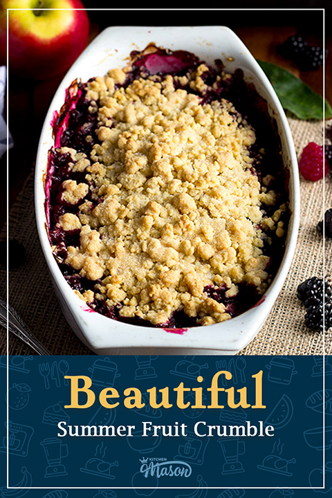 A decorative white dish filled with a bubbling Summer fruit crumble, set on hessian fabric with berries scattered around it. A text overlay says ""Beautiful Summer fruit crumble".