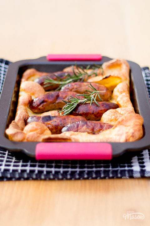 A light, golden and fluffy toad in the hole in a roasting dish on the dining table.