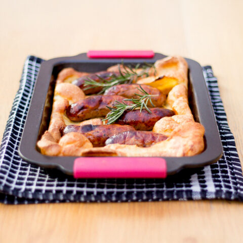 Toad in the hole in a roasting dish on a tea towel.