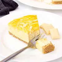 A slice of no bake mango and white chocolate cheesecake on a white plate with a fork.