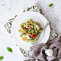Mozzarella Pesto Pasta on a white plate with a fork.